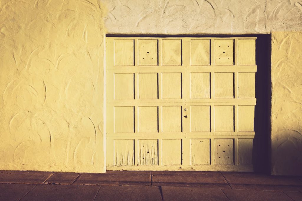 A vintage wooden garage door set against a textured wall in warm, muted tones.